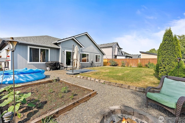 209 Groff Ave NW, Orting, WA 98360 - back of property with a fenced backyard, a fire pit, a vegetable garden, a patio, and a shingled roof