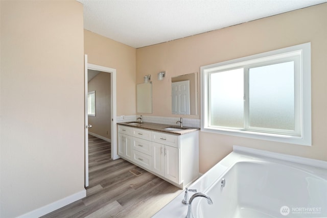 1303 Craig St W, Moses Lake, WA 98837 - bathroom featuring healthy amount of natural light, a bath, double vanity, and wood finished floors