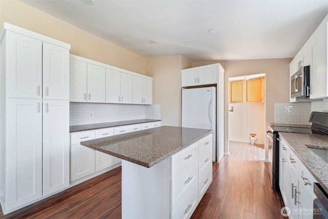 1303 Craig St W, Moses Lake, WA 98837 - kitchen with electric range, stainless steel microwave, backsplash, dark wood-style floors, and dark stone countertops