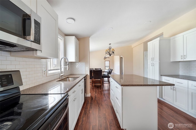 1303 Craig St W, Moses Lake, WA 98837 - kitchen with stainless steel appliances, a chandelier, dark wood-type flooring, dark stone counters, and decorative backsplash