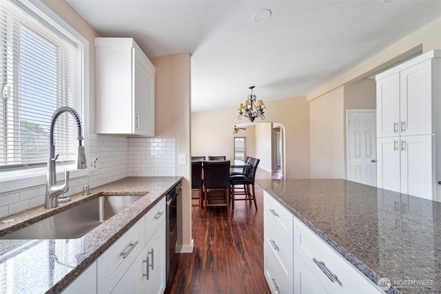 1303 Craig St W, Moses Lake, WA 98837 - kitchen featuring arched walkways, decorative backsplash, dark wood-type flooring, dark stone counters, and a chandelier