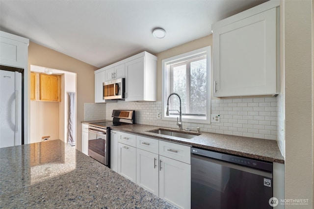 1303 Craig St W, Moses Lake, WA 98837 - kitchen with stainless steel appliances, decorative backsplash, white cabinetry, dark stone countertops, and lofted ceiling