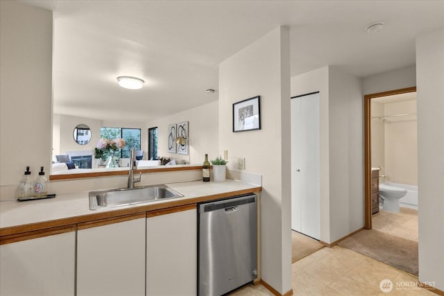 3256 SW Avalon St Unit 304, Seattle, WA 98126 - kitchen featuring stainless steel dishwasher, white cabinets, light countertops, light colored carpet, and light tile patterned floors