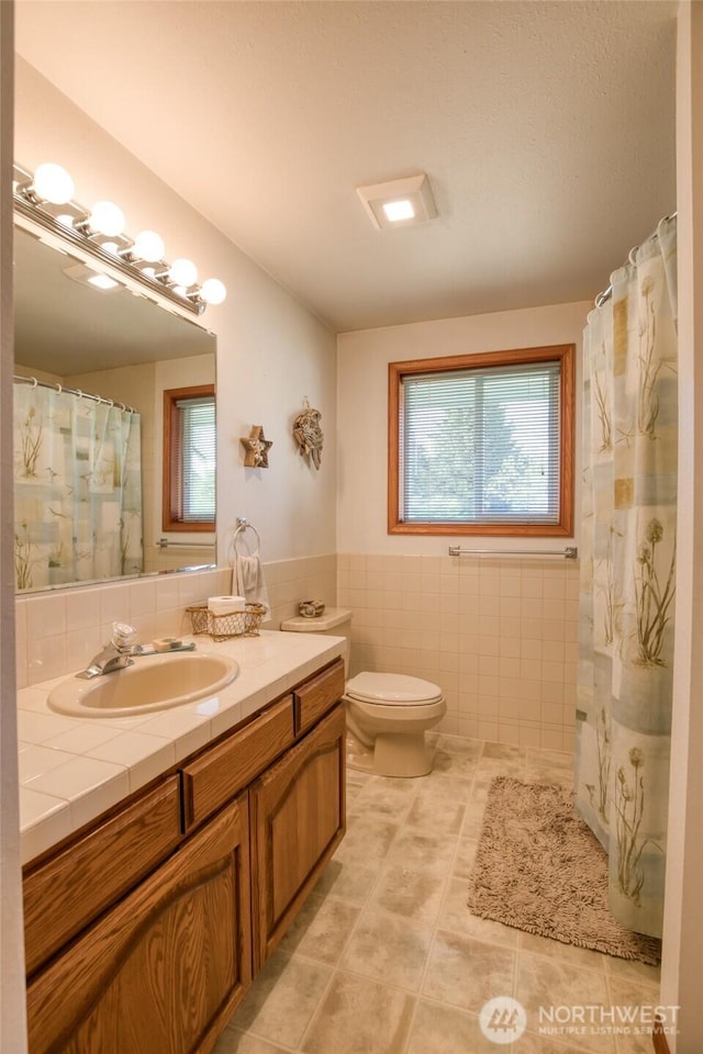 249 Burrows Rd, Hoquiam, WA 98550 - full bath featuring tile walls, plenty of natural light, vanity, tile patterned flooring, and a wainscoted wall