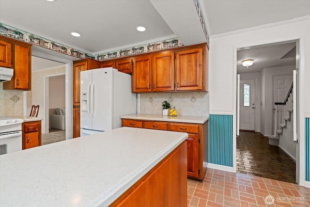 1175 SW Lopez Dr, Oak Harbor, WA 98277 - kitchen with white appliances, light countertops, brick patterned floors, brown cabinetry, and ornamental molding