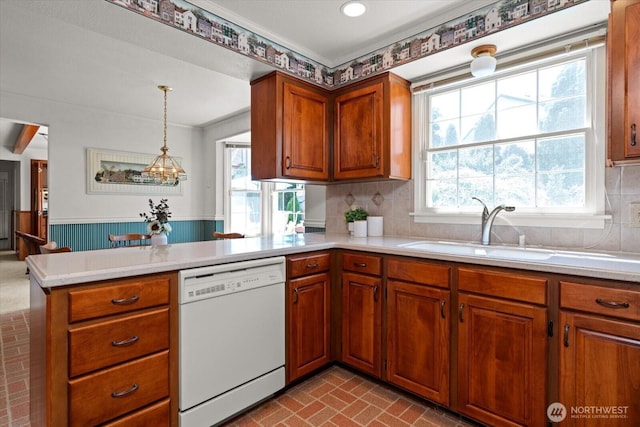 1175 SW Lopez Dr, Oak Harbor, WA 98277 - kitchen featuring dishwasher, a peninsula, light countertops, a wainscoted wall, and brown cabinetry