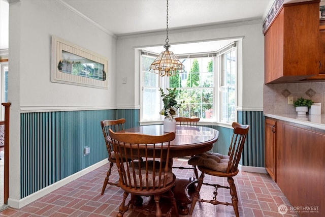 1175 SW Lopez Dr, Oak Harbor, WA 98277 - dining space featuring brick flooring, wainscoting, ornamental molding, and a chandelier