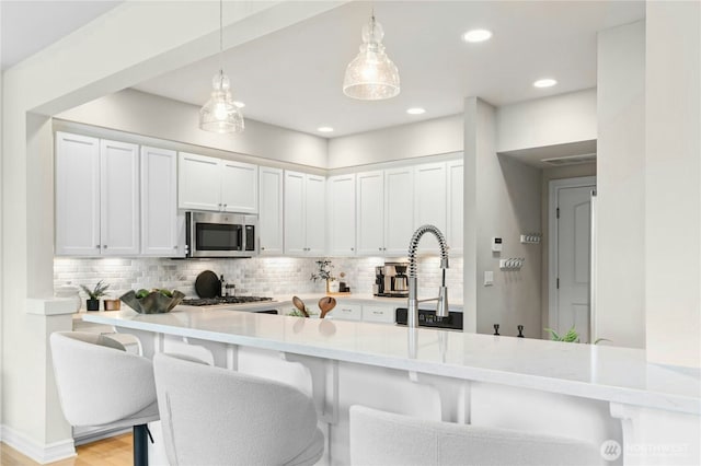 2848 278th Ave SE, Sammamish, WA 98075 - kitchen featuring appliances with stainless steel finishes, backsplash, light countertops, a breakfast bar, and white cabinets