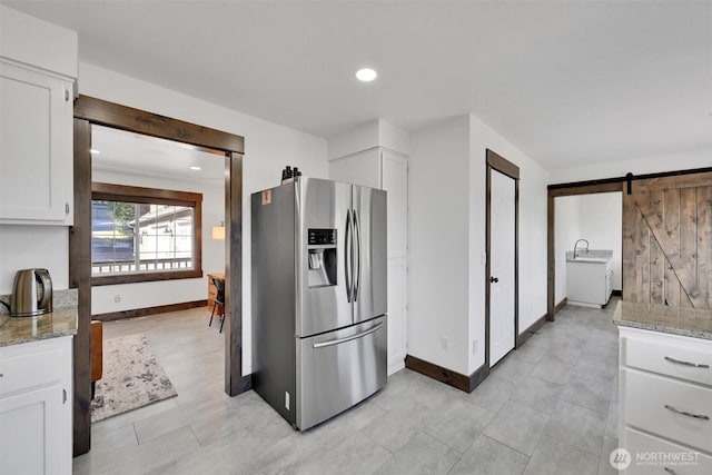 17325 Topaz Loop SE, Yelm, WA 98597 - kitchen featuring stainless steel refrigerator with ice dispenser, white cabinets, a barn door, light stone counters, and recessed lighting