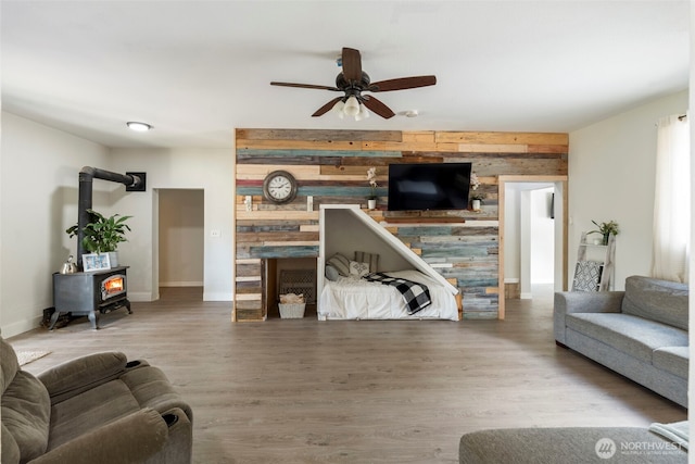253 Kruger Rd Unit B, Onalaska, WA 98570 - living room with a fireplace, a wood stove, wooden walls, ceiling fan, and wood finished floors