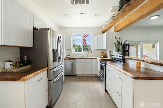 253 Kruger Rd Unit B, Onalaska, WA 98570 - kitchen with wood counters, appliances with stainless steel finishes, decorative backsplash, light wood-style floors, and a peninsula