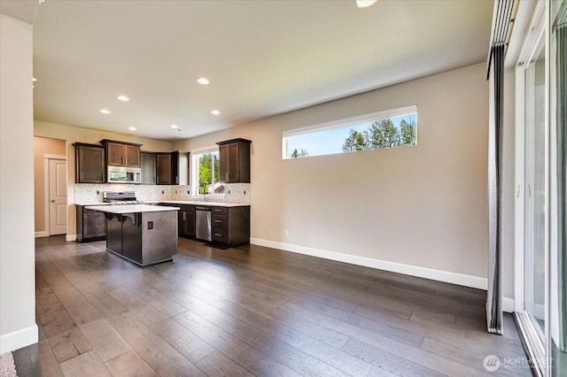 16311 5th Dr SE, Bothell, WA 98012 - kitchen with appliances with stainless steel finishes, dark brown cabinets, a center island, light countertops, and tasteful backsplash