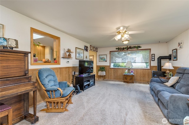 1023 E Maple St, Kent, WA 98030 - carpeted living area featuring wainscoting, wood walls, ceiling fan, and a wood stove