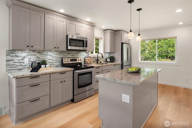4886 24th Ave S, Seattle, WA 98108 - kitchen with appliances with stainless steel finishes, light wood-type flooring, backsplash, a center island, and gray cabinets