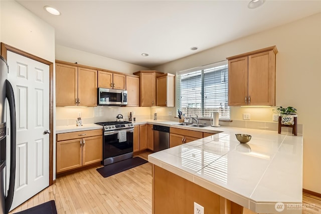 3205 179th Pl SE, Bothell, WA 98012 - kitchen featuring appliances with stainless steel finishes, a peninsula, light wood finished floors, tile countertops, and recessed lighting