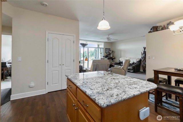 1548 River Rd Unit 301, Longview, WA 98632 - kitchen with brown cabinets, a ceiling fan, dark wood-style floors, light stone counters, and decorative light fixtures