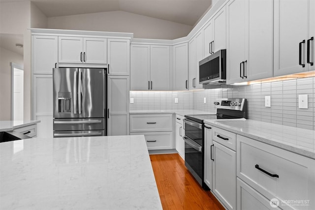 17133 123rd Ct SE, Yelm, WA 98597 - kitchen featuring stainless steel appliances, vaulted ceiling, white cabinetry, light stone counters, and light wood finished floors