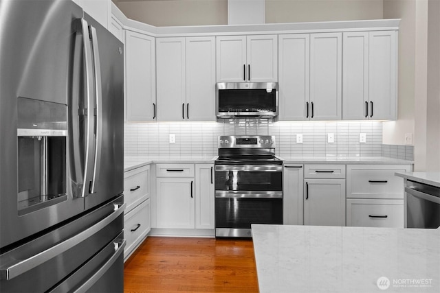 17133 123rd Ct SE, Yelm, WA 98597 - kitchen with appliances with stainless steel finishes, light stone countertops, tasteful backsplash, and white cabinetry