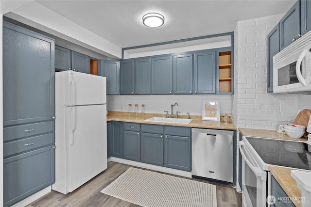 3914 N Gove St, Tacoma, WA 98407 - kitchen with white appliances, blue cabinetry, light wood-type flooring, and light countertops