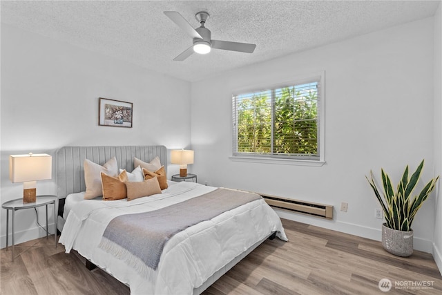 3914 N Gove St, Tacoma, WA 98407 - bedroom with a baseboard heating unit, wood finished floors, a textured ceiling, and a ceiling fan