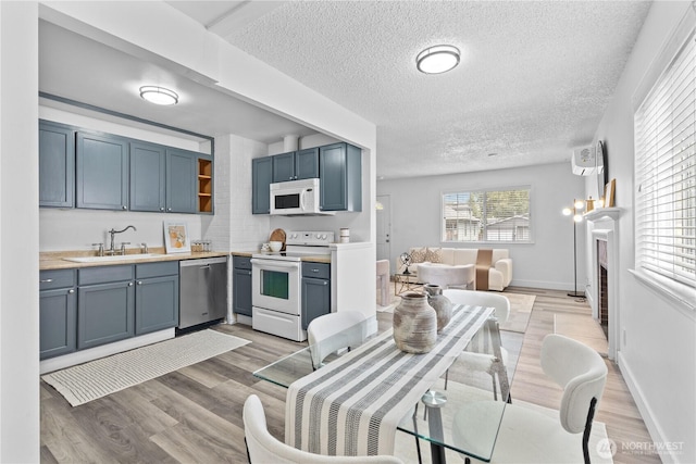3914 N Gove St, Tacoma, WA 98407 - kitchen featuring white appliances, a textured ceiling, light countertops, open shelves, and light wood-style flooring