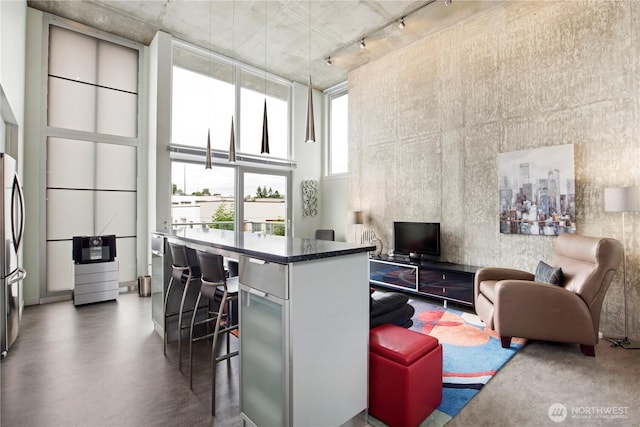 500 Mercer St Unit R325, Seattle, WA 98109 - living area featuring rail lighting, a towering ceiling, and finished concrete floors