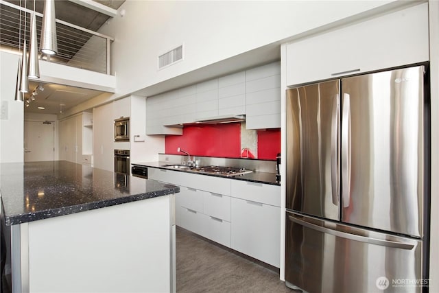 500 Mercer St Unit R325, Seattle, WA 98109 - kitchen featuring stainless steel appliances, white cabinets, modern cabinets, a towering ceiling, and dark stone counters