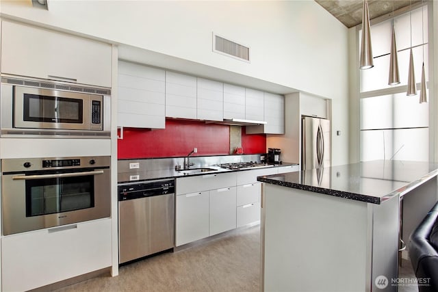 500 Mercer St Unit R325, Seattle, WA 98109 - kitchen featuring appliances with stainless steel finishes, white cabinetry, dark countertops, modern cabinets, and tasteful backsplash