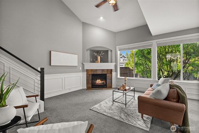 32216 Bruckners Way, Black Diamond, WA 98010 - carpeted living area with ceiling fan, a decorative wall, a tiled fireplace, vaulted ceiling, and a wainscoted wall