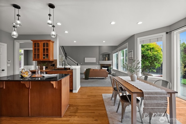 32216 Bruckners Way, Black Diamond, WA 98010 - kitchen with a fireplace, brown cabinetry, glass insert cabinets, light wood-style floors, and a kitchen bar
