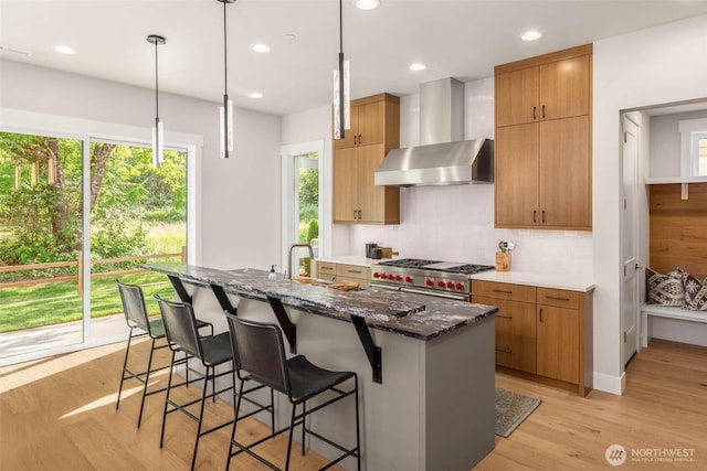 21025 SE 80th St, Issaquah, WA 98027 - kitchen with wall chimney exhaust hood, high end stainless steel range, backsplash, dark stone countertops, and light wood-style floors
