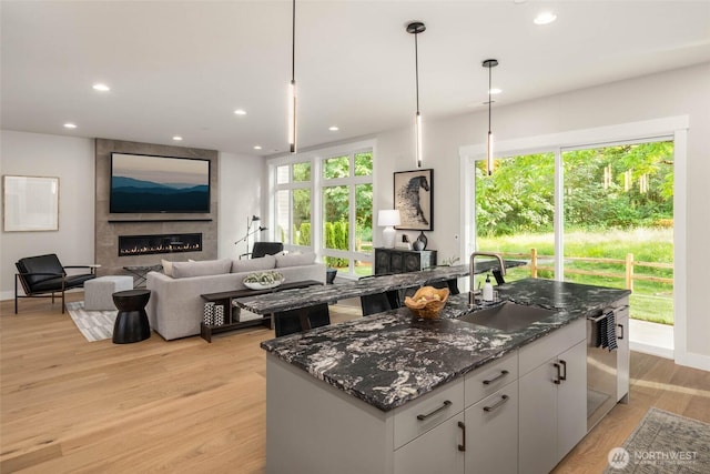 21025 SE 80th St, Issaquah, WA 98027 - kitchen featuring a fireplace, dark stone counters, a center island, light wood finished floors, and white cabinetry
