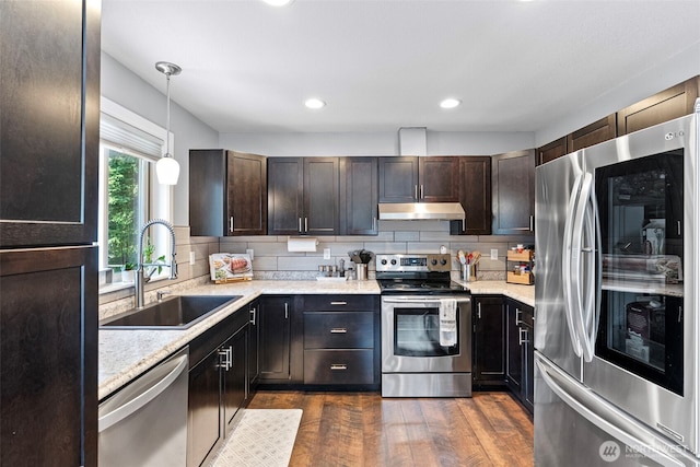 134 Robin Ln, Port Ludlow, WA 98365 - kitchen featuring stainless steel appliances, under cabinet range hood, decorative backsplash, dark brown cabinets, and decorative light fixtures
