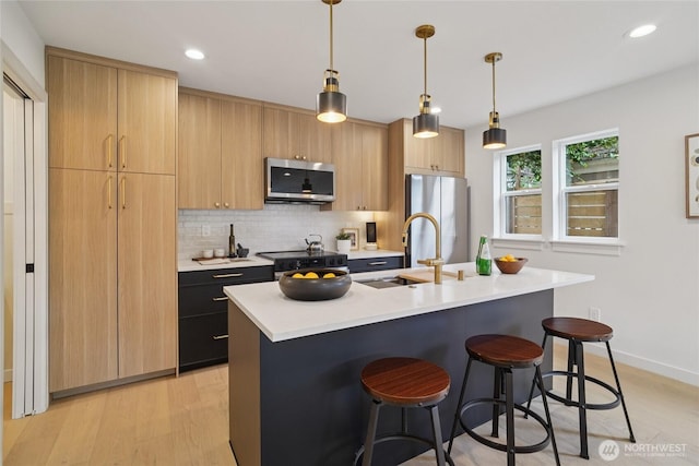 8227 Latona Ave NE, Seattle, WA 98115 - kitchen with appliances with stainless steel finishes, light countertops, a center island with sink, light wood finished floors, and decorative backsplash