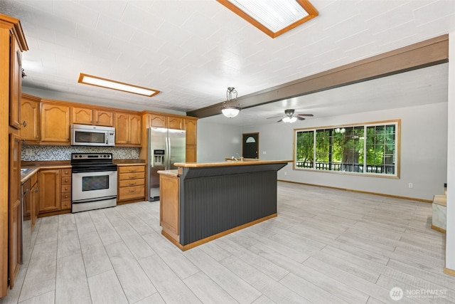 262 Falls Rd, Randle, WA 98377 - kitchen featuring appliances with stainless steel finishes, brown cabinets, a kitchen island, open floor plan, and light wood finished floors