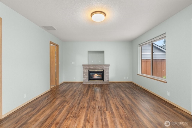 5411 Komachin Loop SE, Lacey, WA 98513 - unfurnished living room with wood finished floors, a brick fireplace, and a textured ceiling