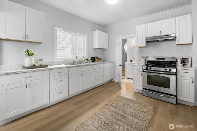 1103 E 59th St, Tacoma, WA 98404 - kitchen with stainless steel range with gas cooktop, under cabinet range hood, white cabinets, light wood finished floors, and light stone counters