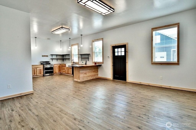 132 Milky Way, Sequim, WA 98382 - kitchen featuring stainless steel stove, a peninsula, wood finished floors, open floor plan, and hanging light fixtures