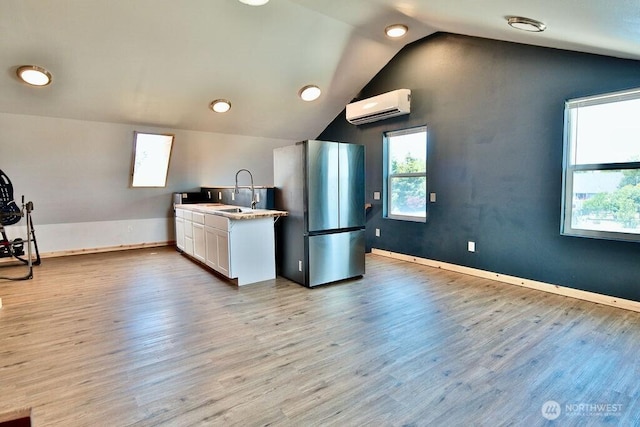 132 Milky Way, Sequim, WA 98382 - kitchen featuring freestanding refrigerator, a wall mounted air conditioner, white cabinetry, lofted ceiling, and light wood-style floors