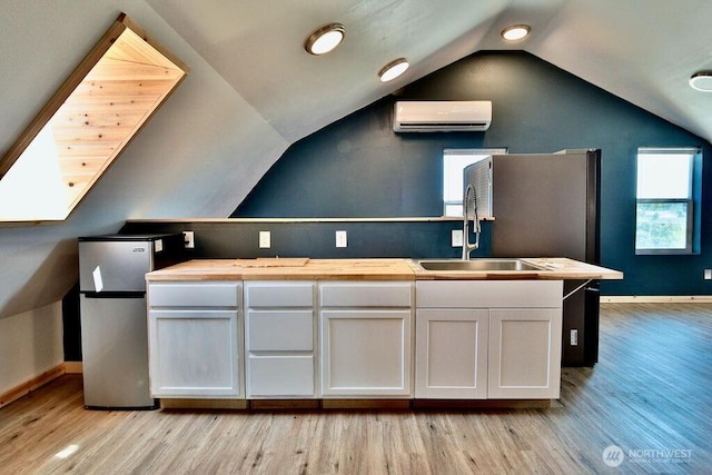 132 Milky Way, Sequim, WA 98382 - kitchen with a wall mounted AC, freestanding refrigerator, light wood-style flooring, lofted ceiling, and wooden counters