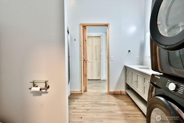 132 Milky Way, Sequim, WA 98382 - laundry area with stacked washer and clothes dryer, light wood-type flooring, and cabinet space