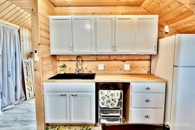 132 Milky Way, Sequim, WA 98382 - kitchen featuring freestanding refrigerator, wooden walls, light countertops, light wood-style floors, and wooden ceiling