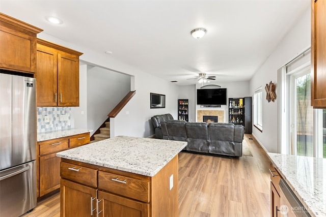 815 6th Ave SW, Olympia, WA 98512 - kitchen with freestanding refrigerator, ceiling fan, light wood-style floors, a lit fireplace, and brown cabinetry