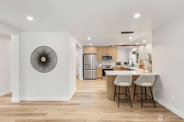 840 NE 100th St Unit A, Seattle, WA 98125 - kitchen featuring stainless steel appliances, light countertops, a peninsula, a kitchen bar, and recessed lighting