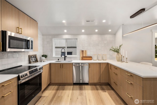 840 NE 100th St Unit A, Seattle, WA 98125 - kitchen with appliances with stainless steel finishes, a peninsula, light wood-style flooring, backsplash, and light countertops