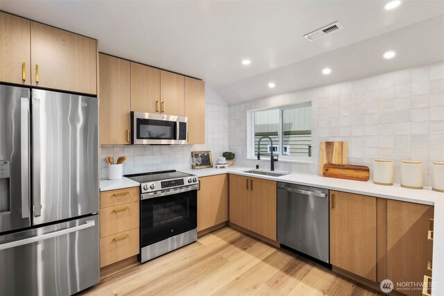840 NE 100th St Unit A, Seattle, WA 98125 - kitchen featuring stainless steel appliances, tasteful backsplash, light countertops, light wood-type flooring, and vaulted ceiling