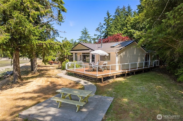 7717 176th Ave SW, Longbranch, WA 98351 - rear view of property featuring a lawn, a wooden deck, a metal roof, and a standing seam roof