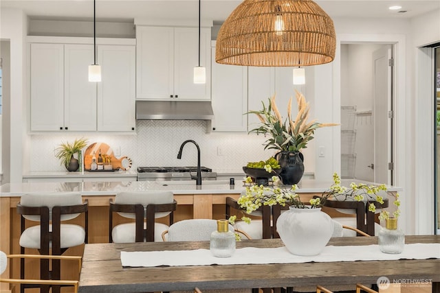3052 SE 13th Pl, North Bend, WA 98045 - kitchen with under cabinet range hood, decorative backsplash, pendant lighting, light countertops, and a kitchen breakfast bar