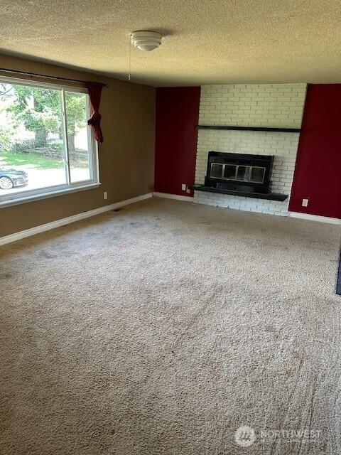129 W Washington St, Napavine, WA 98565 - unfurnished living room featuring a textured ceiling, a fireplace, and carpet flooring