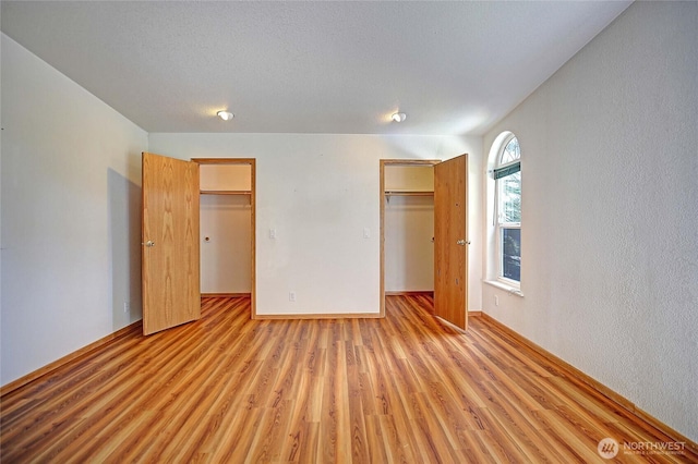 832 Margie Ann Dr, Camano Island, WA 98282 - unfurnished bedroom featuring a walk in closet, a closet, light wood finished floors, and a textured wall